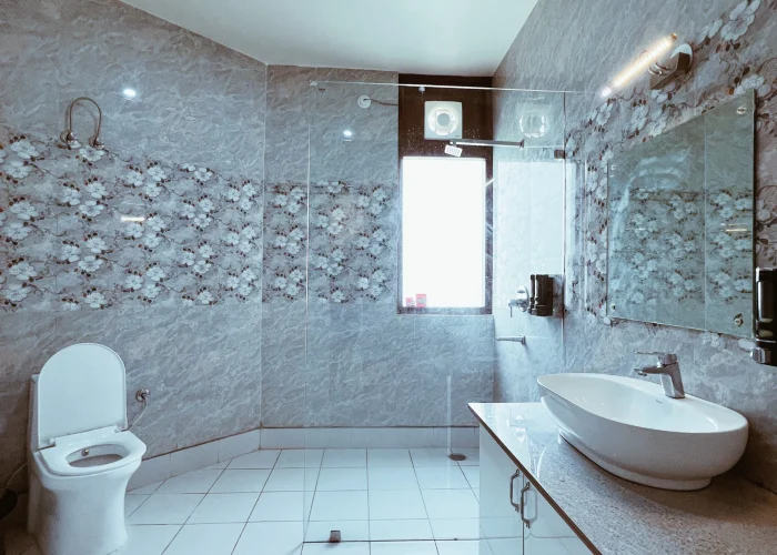 Modern hotel bathroom with a clean Western toilet, shower area, and toiletries